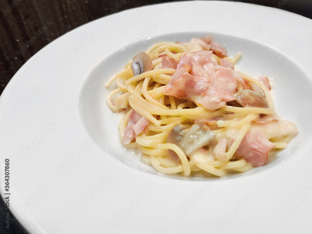 Spaghetti alla Carbonara serving on white plate, spaghetti with pancetta, egg, hard parmesan cheese and cream sauce. Traditional italian dish Spaghetti alla Carbonara serving on white plate, spaghetti with pancetta, egg, hard parmesan cheese and cream sauce. Traditional italian dish