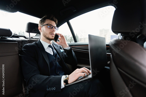 Young businessman talking on phone in car using his pc © Prostock-studio