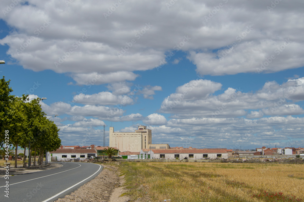road and field with buildings and sky with clouds in Torrijos province of Toledo. Spain