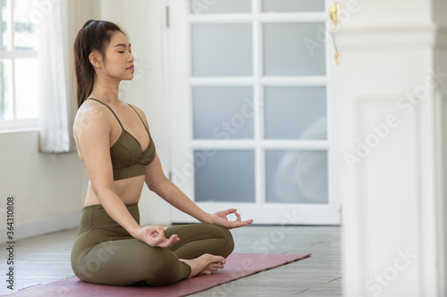 Attractive Asian woman exercise yoga lotus pose to meditation at home
