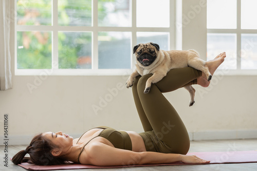 Asian young woman practice yoga with dog pug breed relax at home photo