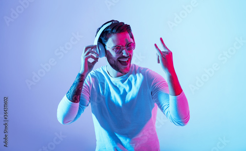 Joyful emotion concept. Guy in headphones dances to favorite music and shows cool sign