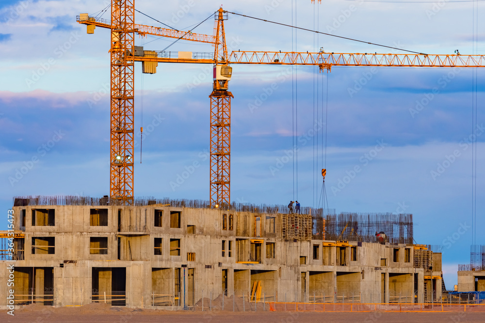 Construction site against the blue sky. The frame of the future building and cranes. Construction business. Sale of apartments in buildings under construction. Construction site against the blue sky. The frame of the future building and cranes. Construction business. Sale of apartments in buildings under construction.