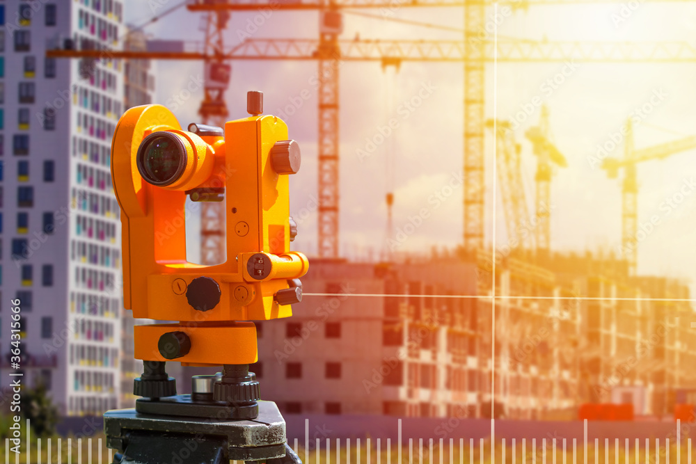 A surveyor works on a construction site. Measuring equipment in construction. Theodolite projects a measuring grid on a house under construction. A surveyor works on a construction site. Measuring equipment in construction. Theodolite projects a measuring grid on a house under construction.