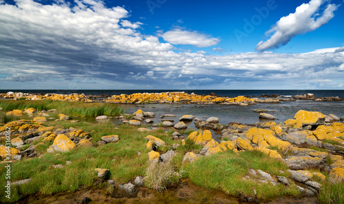Granit Küste vor der dänischen Stadt Svaneke auf der Insel Bornholm mit grau-gelben Steinen vor einem bewölkten Himmel im Sommer
