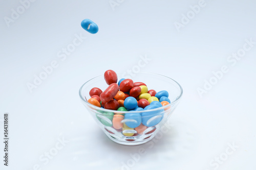 Colorful candy in a glass bowl on white background 