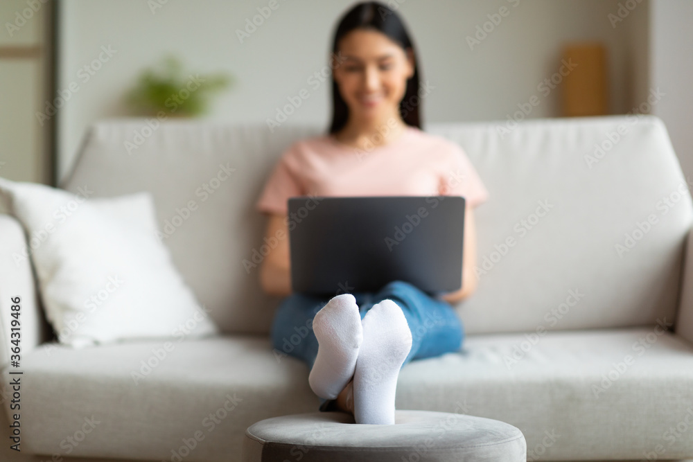 Woman Using Laptop Working Online From Home Sitting On Sofa