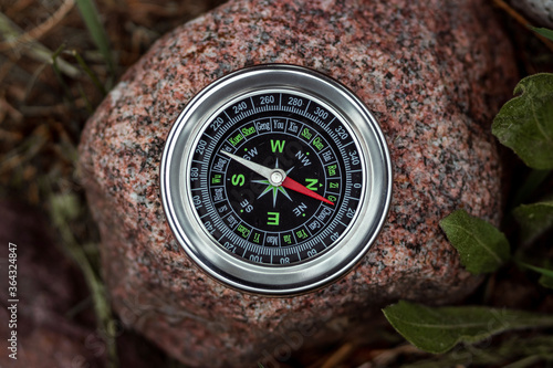Magnetic compass with a black dial on a stone top view. The concept of travel, finding a path, achievement, hiking, vacation. Copy space.