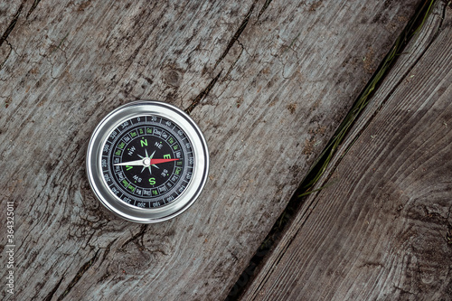 Silver compass on a wooden background top view. The concept of travel, leadership, help. Copy space.