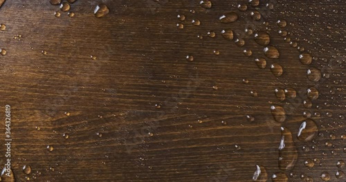 Raindrops on a wooden board. The wind blows off drops of water.