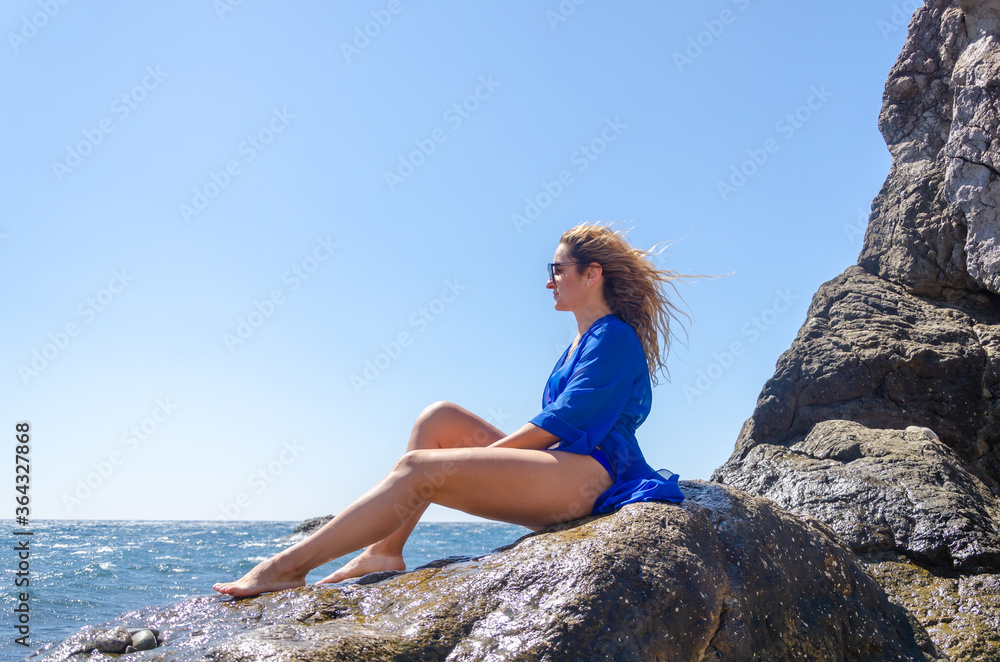 Attractive young woman in blue swimsuit on sea coast Attractive young woman in blue swimsuit on sea coast
