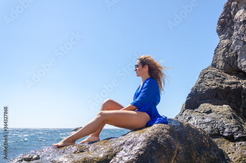 Attractive young woman in blue swimsuit on sea coast