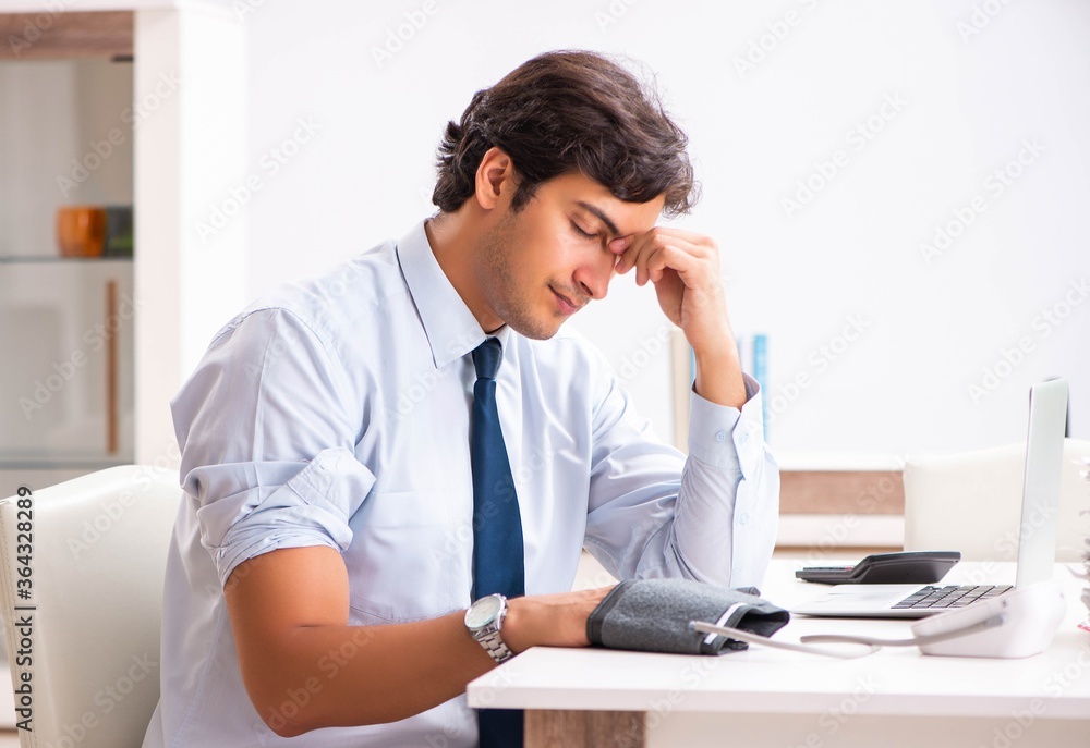 Man under stress measuring his blood pressure Man under stress measuring his blood pressure
