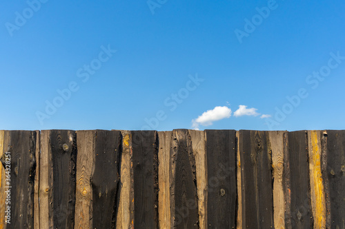 Blue sky over a high wooden fence