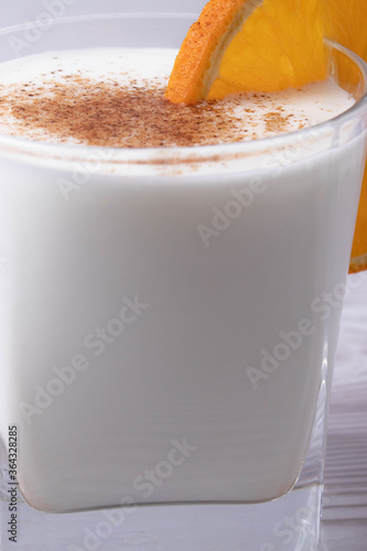 sweet milky desert or coconut milk and a slice of orange in a glass