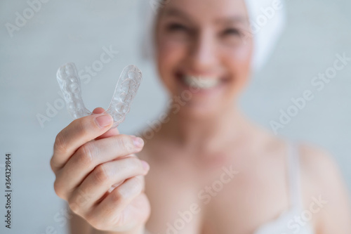 Fototapeta A woman with a towel on her head holds a whitening mouth guard for teeth