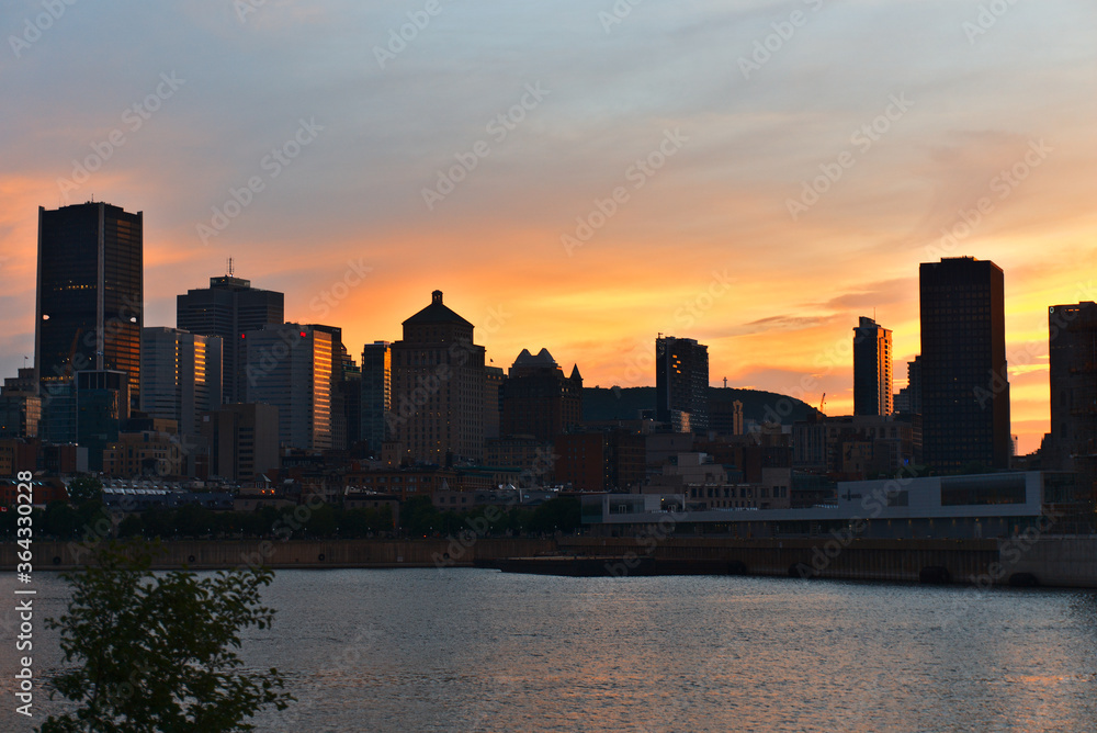 Montreal Downtown skyline at the time between sunset and twilight. Reflections of sun rays on Saint Laurent river.