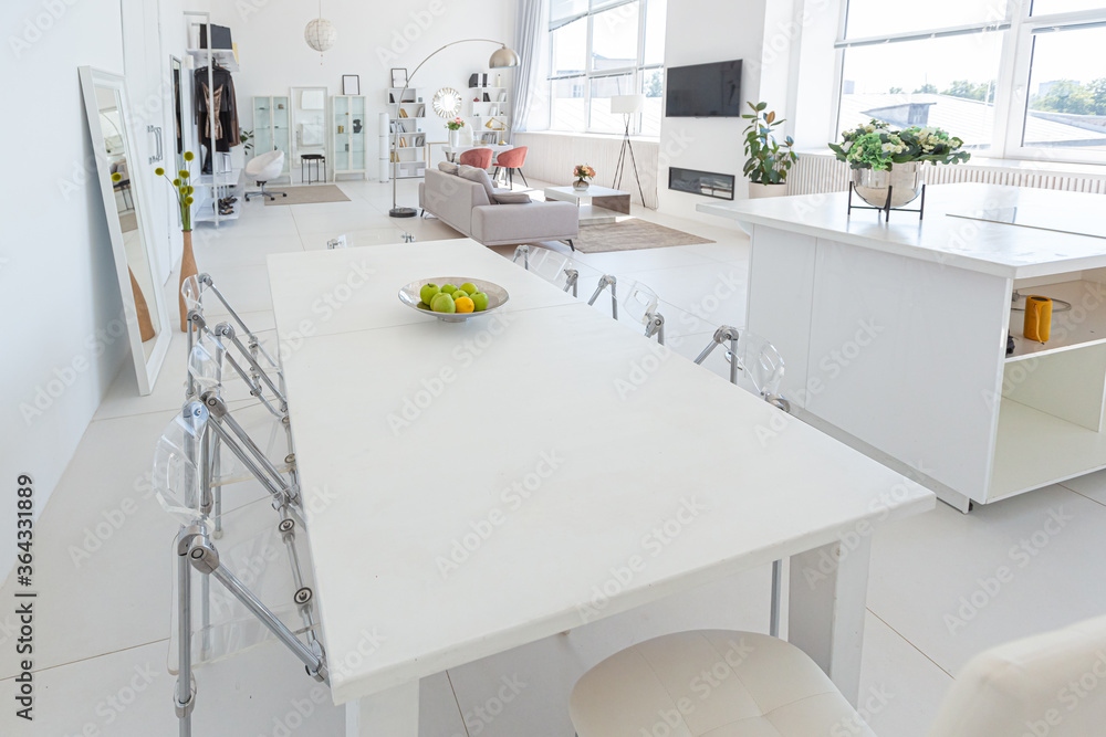 Cozy luxury modern interior design of a studio apartment in extra white colors with fashionable expensive furniture in a minimalist style. white tiled floor, kitchen, relaxation area and workplace Cozy luxury modern interior design of a studio apartment in extra white colors with fashionable expensive furniture in a minimalist style. white tiled floor, kitchen, relaxation area and workplace