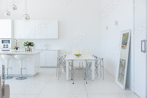 Fototapeta Naklejka Na Ścianę i Meble -  Cozy luxury modern interior design of a studio apartment in extra white colors with fashionable expensive furniture in a minimalist style. white tiled floor, kitchen, relaxation area and workplace