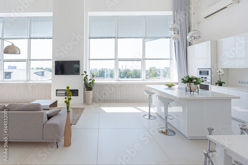 Cozy luxury modern interior design of a studio apartment in extra white colors with fashionable expensive furniture in a minimalist style. white tiled floor  kitchen  relaxation area and workplace