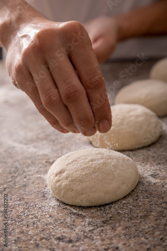  woman hands sprinkling pizza flour close-up
