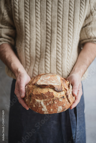 Baked bread of sourdough in hands. Artisan bread. The bread of sourdough, homemade and natural creation. The sourdough has natural yeast, which makes the food healthier, as well as rich.