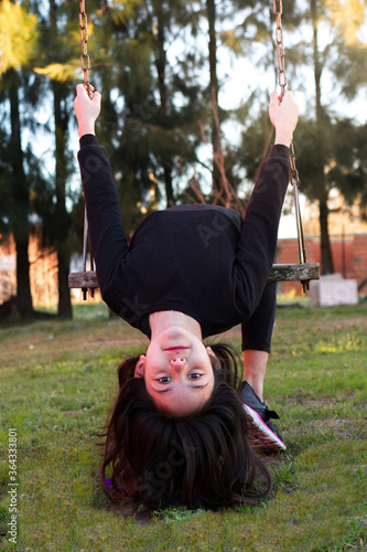 portrait of little girl with head upside down in swing