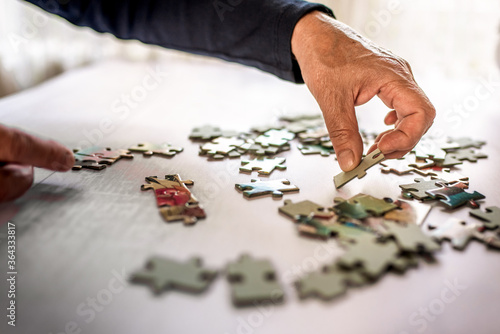 Cuadro en lienzo Old hand picking a jigsaw puzzle piece