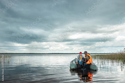 Grandfather and grandson ride a motor boat on the lake. The concept of family, summer vacation, generation. Copy space.