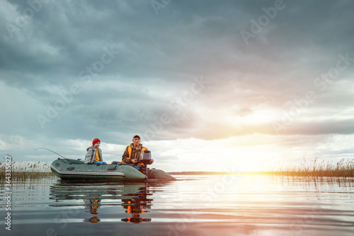 Father and son ride a motor boat on the lake. The concept of family, summer vacation, generation. Copy space.