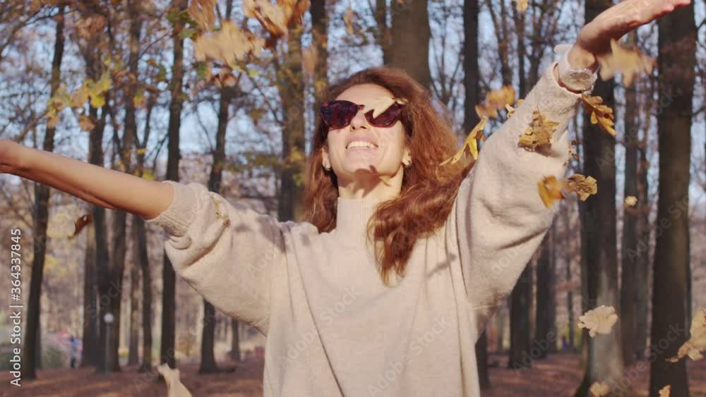 Girl tossing colorful autumn foliage up in air in park. Girl tossing colorful autumn foliage up in air in park.