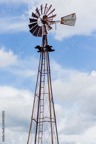 old windmill against blue sky with clouds