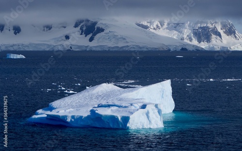 Iceberg in blue Antarctic sea, before mountain with stormy sky , Antarctica