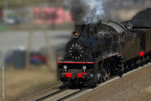Retro steam train in puffs of smoke rides by rail