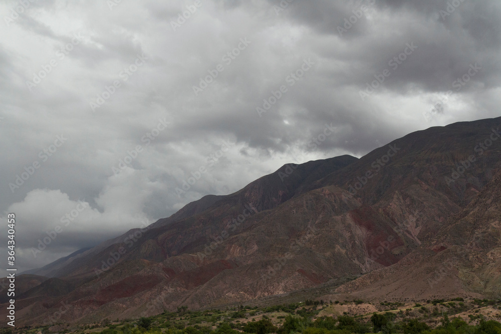 Cloudscape. Panorama view of the brown arid mountain under a dramatic cloudy sky. 