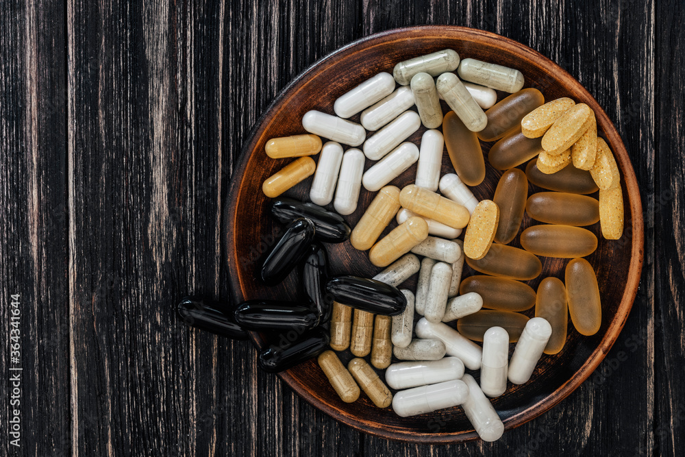 Multivitamin pills on a clay plate, on a vintage wooden table Multivitamin pills on a clay plate, on a vintage wooden table