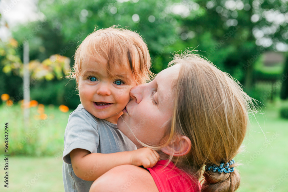 Mother kissing baby on cheek Mother kissing baby on cheek