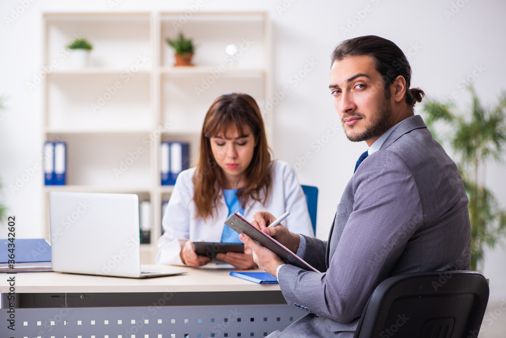 Young female doctor and sick businessman in the office Young female doctor and sick businessman in the office