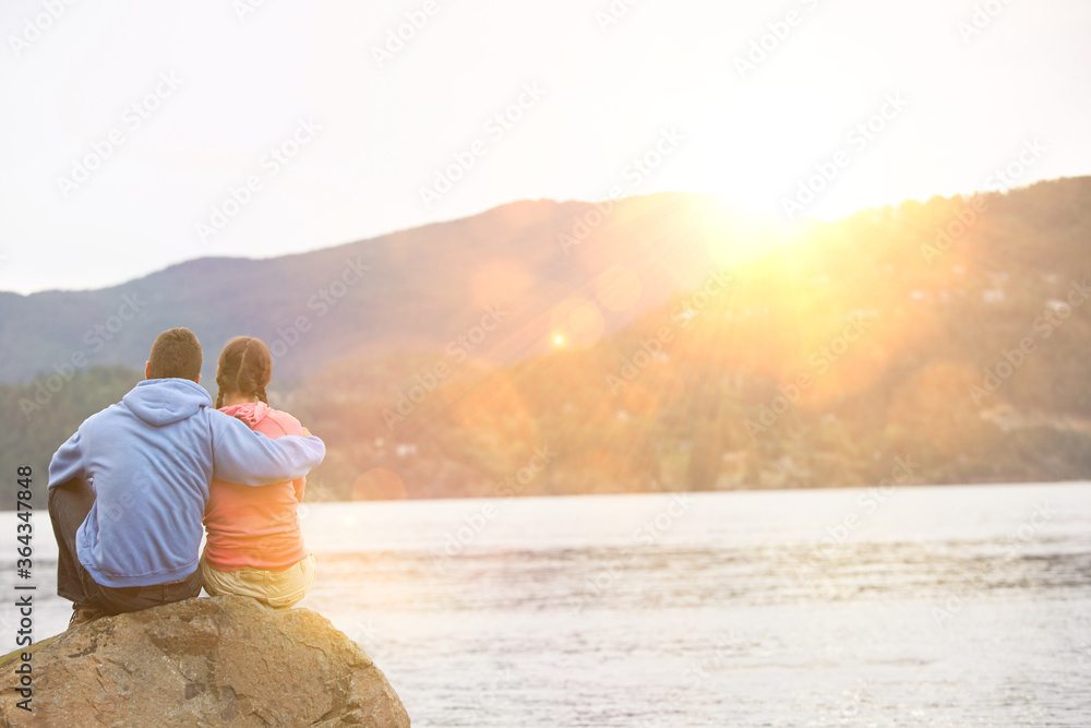 Couple hugging sitting by lake Couple hugging sitting by lake