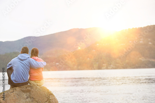 Couple hugging sitting by lake © moodboard