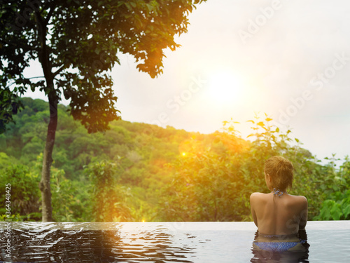 Young Woman in Swimming Pool at sunset