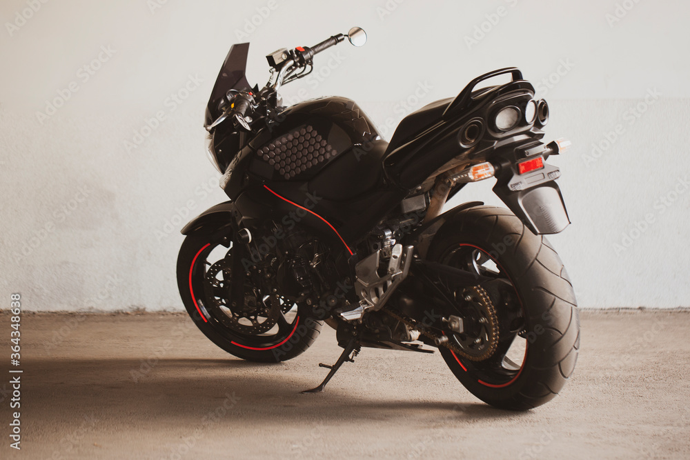 Sports black motorcycle on a background of an underground gray wall in the studio. Sports black motorcycle on a background of an underground gray wall in the studio.