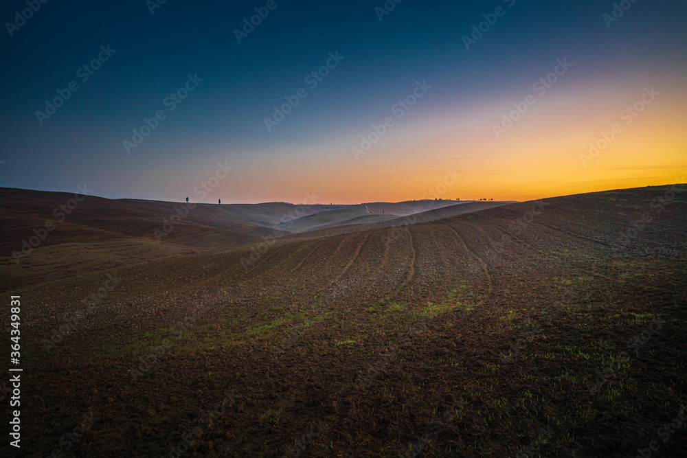 Beautiful wide angle view of sunrise over the Tuscany fields and hills