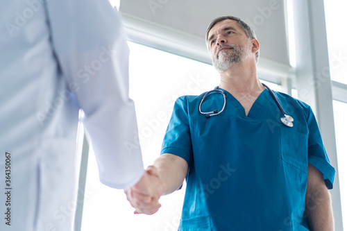 Two medical people handshaking at office, in hospital.