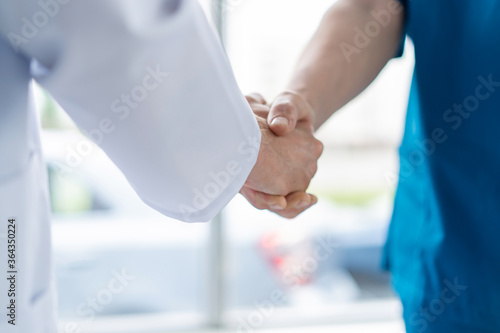Two medical people handshaking at office, in hospital.