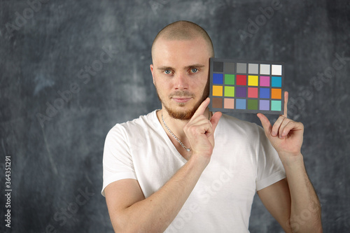 The model holds a color card in its hands for correct color transfer during further color correction. Color checker card.