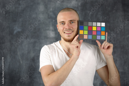 The model holds a color card in its hands for correct color transfer during further color correction. Color checker card.
