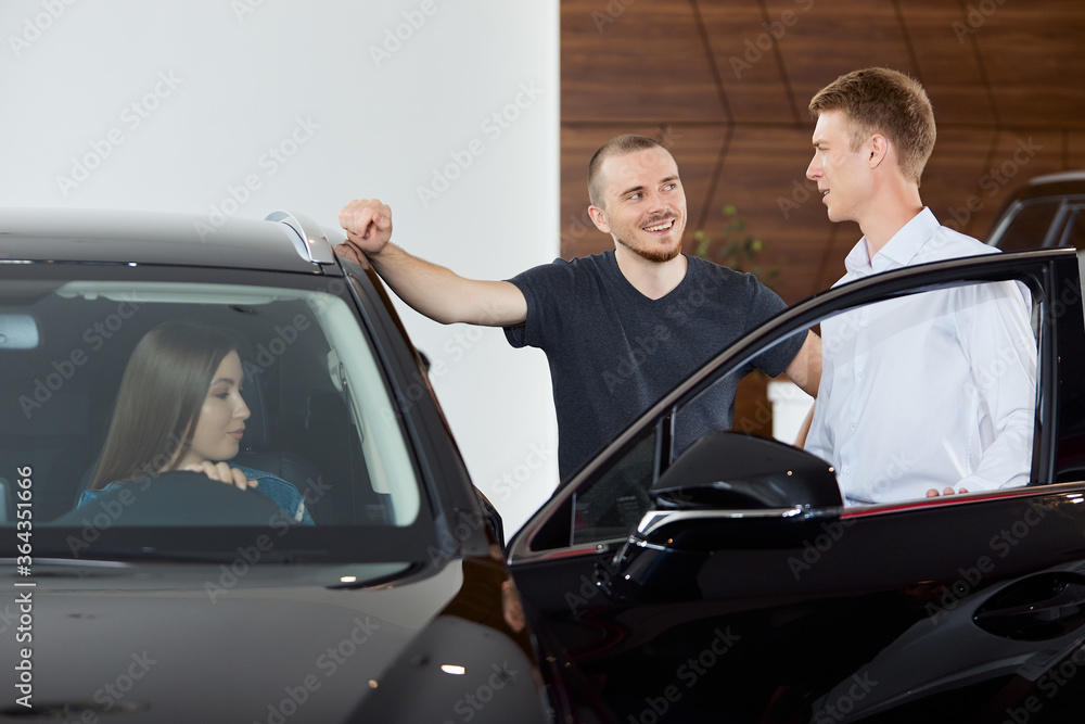 A sales representative explains the pros and cons of a brand new car at a dealership. Concept professionalism agreement contract leasing renting retail car sales