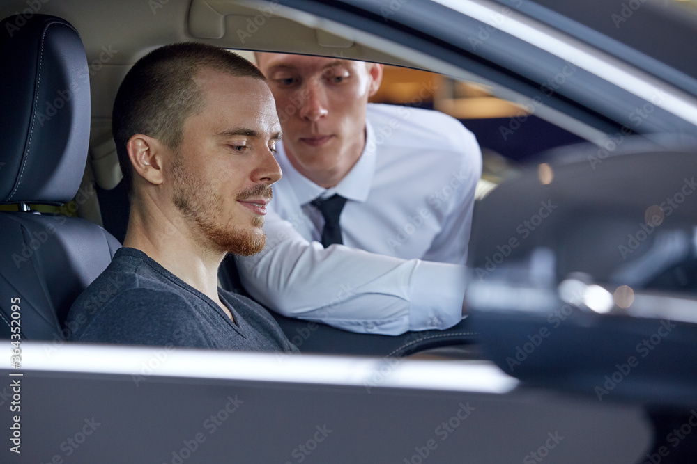Selective focus on a young person choosing a new car while communicating with the seller Selective focus on a young person choosing a new car while communicating with the seller