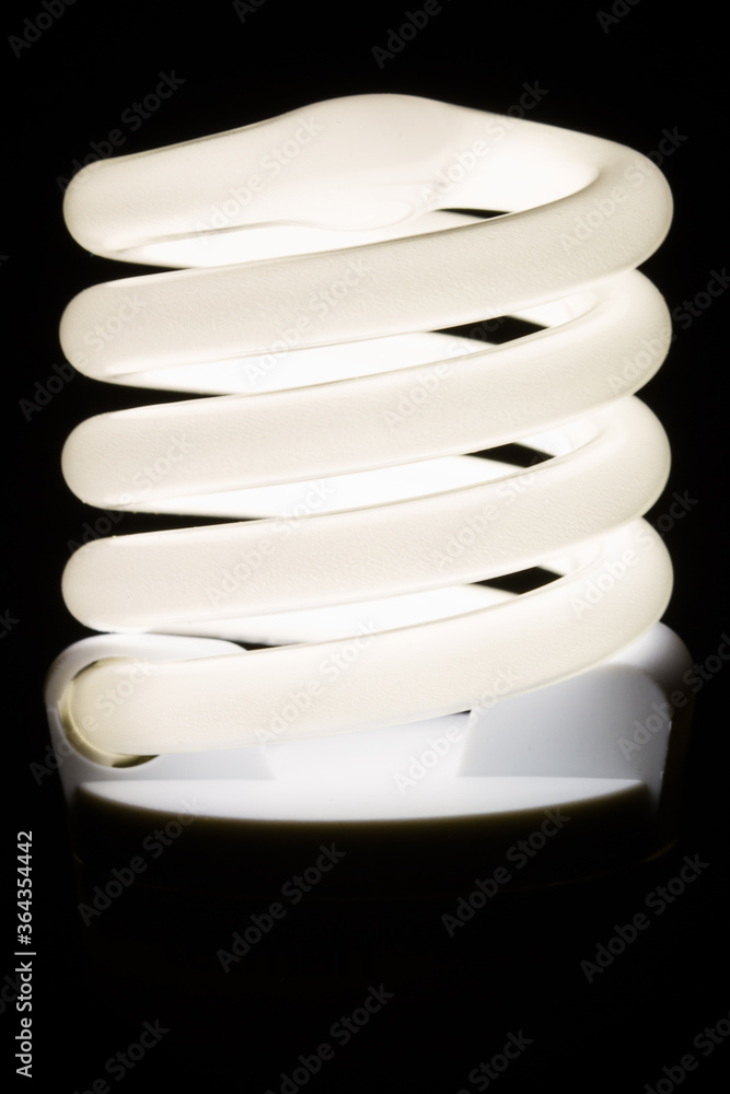 Fluorescent light bulb isolated on black background. Economical home lighting. Energy saving concept. Fluorescent light bulb isolated on black background. Economical home lighting. Energy saving concept.